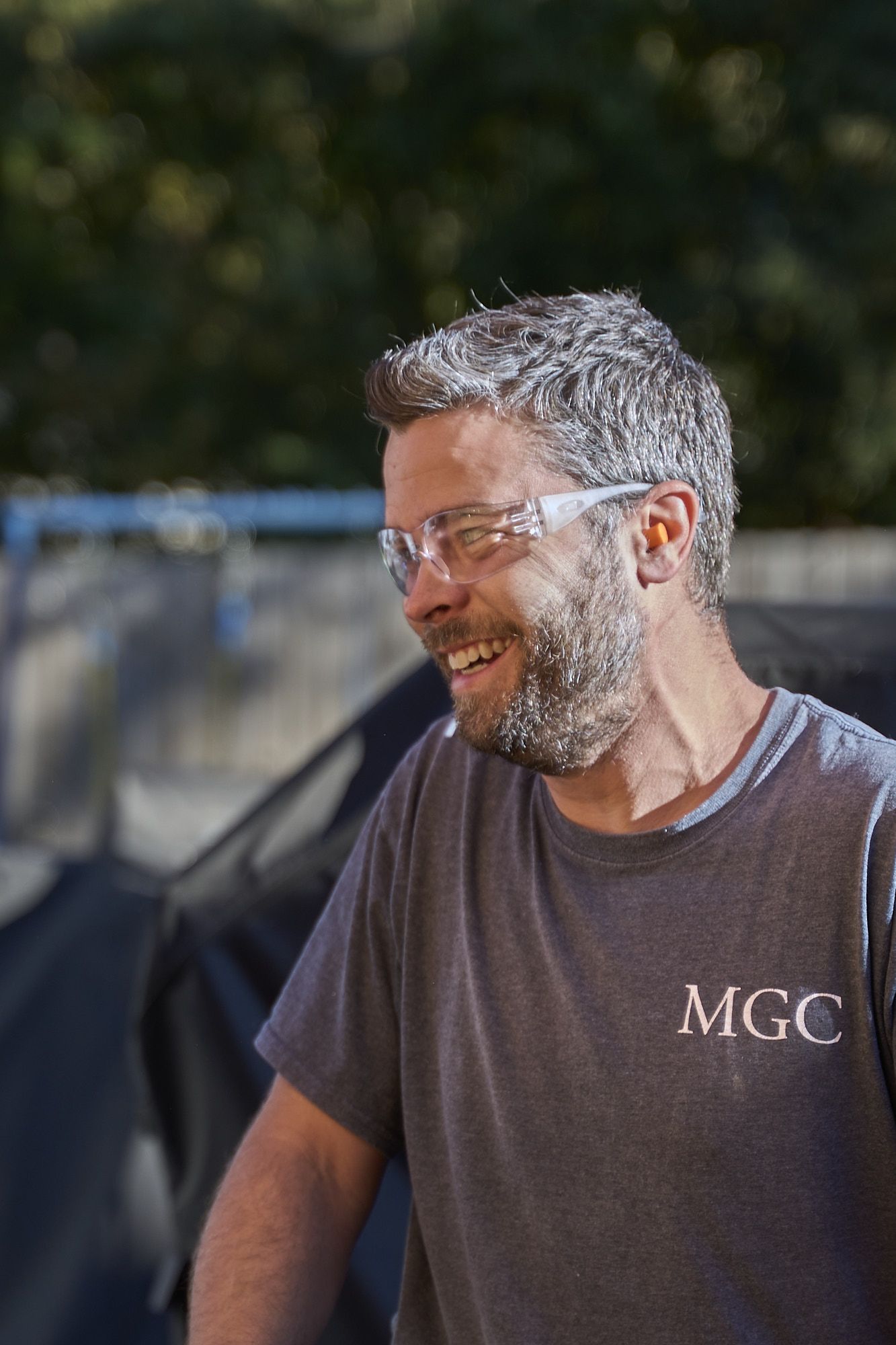 Smiling Contractor Wearing Safety Glasses And Ear Protection During Outdoor Construction And Remodeling Project